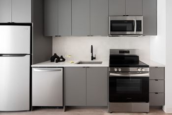 A modern kitchen with a white refrigerator, microwave, and stainless steel appliances.
